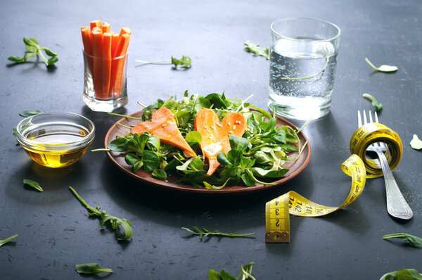 Concept diet food. Salad with arugula, leaf mash and carrots on a dark background. Vegetarian healthy dish that promotes weight loss.