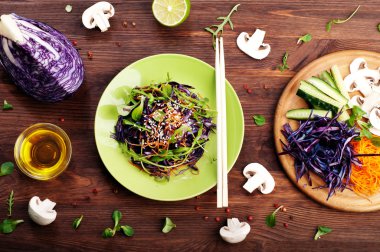 Concept diet food. Delicious vegetarian salad of arugula, leaf mash, purple cabbage and carrots on a brown wooden background. Natural organic healthy food, ready-to-eat