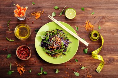 Concept diet food. Delicious vegetarian salad of arugula, leaf mash, purple cabbage and carrots on a brown wooden background. Natural organic healthy food, ready-to-eat