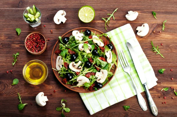 Salad with arugula, leaf mash, olives, sun-dried tomatoes and raw mushrooms. The concept of diet vegetarian food homemade — Stok fotoğraf