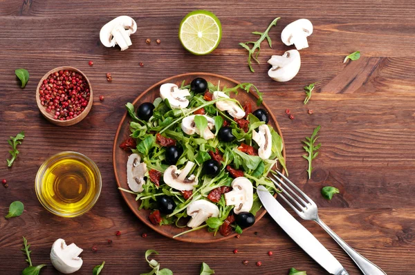 Salad with arugula, leaf mash, olives, sun-dried tomatoes and raw mushrooms. The concept of diet vegetarian food homemade — Stock Photo, Image