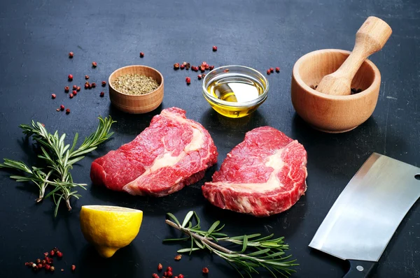 ステーキを調理するために調理された生の牛肉。ステーキ、スパイス、ハーブを調理するための材料の横に. — ストック写真