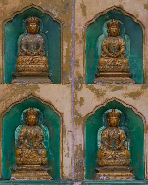 Golden Buddha statues along the wall in the interior of the Linh