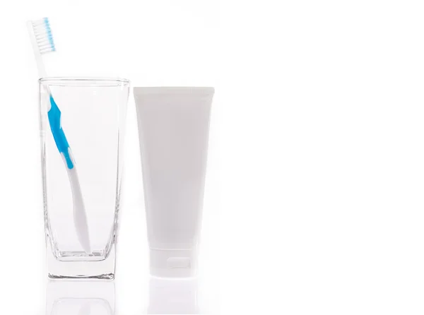Οδοντόβουρτσα σε ένα διαφανές γυαλί και οδοντόκρεμα σε άσπρο φόντο — Φωτογραφία Αρχείου