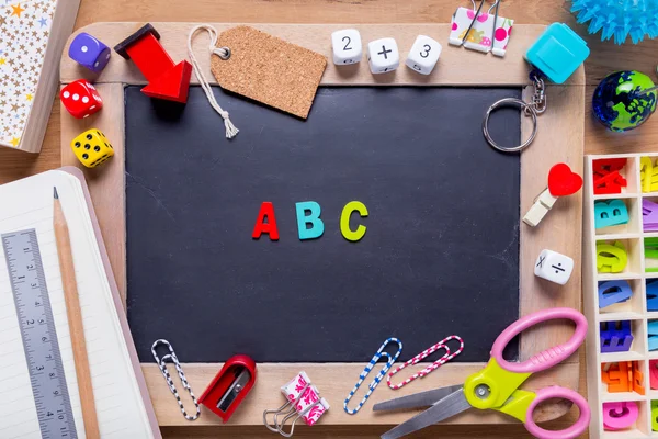 Kleine Tafel umgeben von verschiedenen Schreibwaren mit einem b c a — Stockfoto