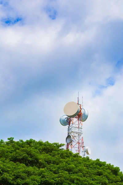 Torre di telecomunicazione con alberi verdi e cielo azzurro nuvoloso — Foto Stock