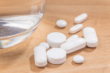 Bardak su ahşap arka plan üzerinde beyaz hap