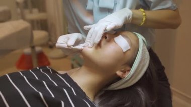 Genç Asyalı kadın sivilce ve yüz bakımı yaptırıyor.