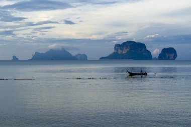 Balıkçı teknesinde bir adam sabah balığından dönüyor. Pranang Mağara Sahili, Railay, Krabi, Tayland 'da güzel bir sabah ışığında.