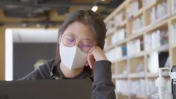 Zmęczona Młoda Azjatycka Studentka Nastolatka Nosząca Maskę Medyczną Słuchawki Podczas — Wideo stockowe