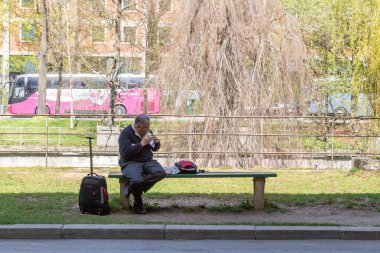 Münih, Almanya - 15 Nisan 2015 - Bir erkek turist öğle yemeğini tek başına yemek için kaldırım kenarında oturuyor