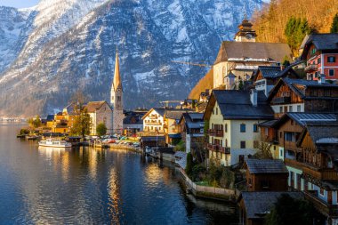 Güzel Hallstatt Gölü ve ünlü kilisenin manzarası ilkbaharın erken saatlerinde sabah erken saatlerde, dağ sıraları karla kaplanmış.