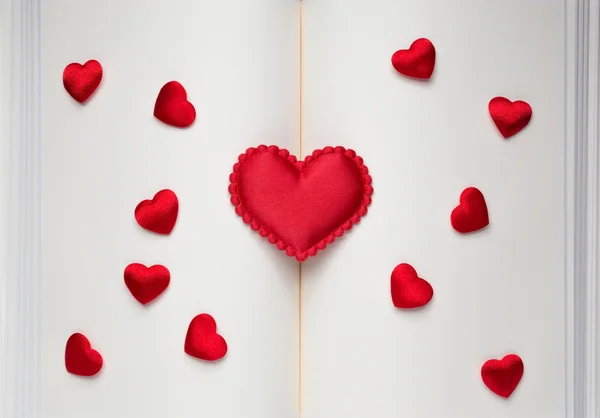 Великі і маленькі червоні серця на відкритій книзі — стокове фото