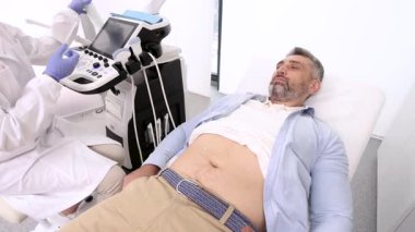 Hastanedeki ultrason makinesi olan erkek hasta için ultrason uzmanı karın boşluğu ultrasonografisi yapıyor.