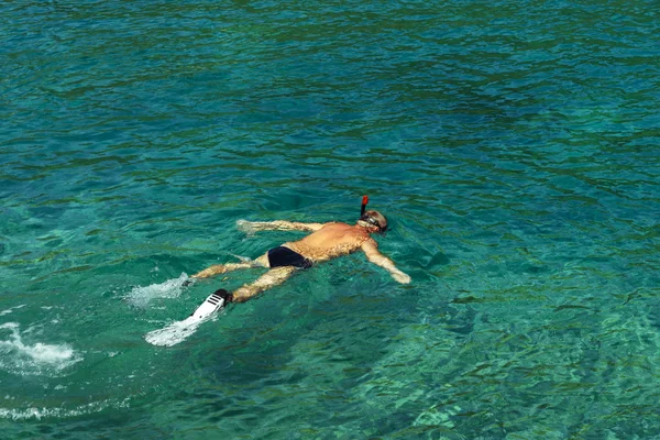 Snorkeling uomo con pinne, maschera e snorke in pigrizia, acqua di mare limpida del Mare Adriatico. Frammenti di luce solare nell'acqua di mare. Vista dall'alto del nuotatore — Foto Stock