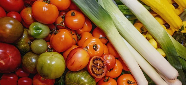 Овощи, помидоры различных сортов желтый, зеленый, красный, черный, и цуккини, лук-порей — стоковое фото