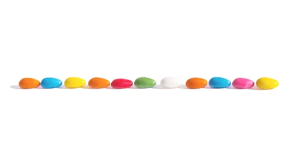 Кольорові цукерки у вигляді яєць, викладених у лінію. Горизонтальна межа над білим. На Великоднє привітання — стокове фото