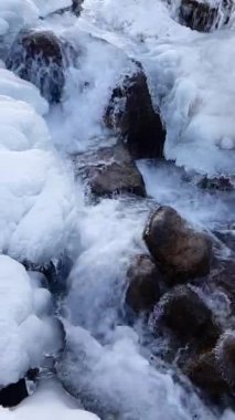 Buzun arasındaki bir dağ nehrinde su akıntısı.