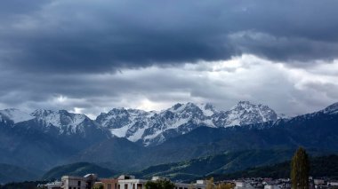 Almaty 'deki karlı dağ tepelerinin üzerindeki bulutlar.