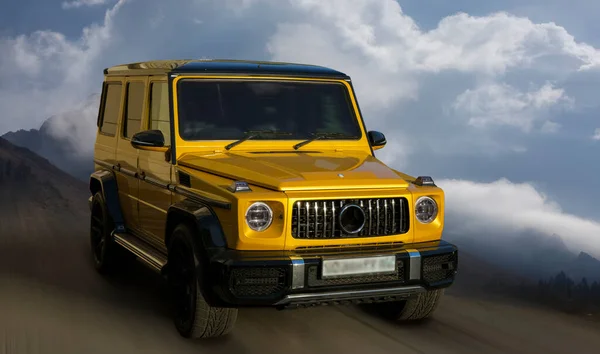 Mercedes Benz Gelenvagen sarı araba hareket halindeki bulanık arkaplanda.