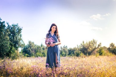 Bir sonbahar tarlasında elinde çiçeklerle bir kadının portresi