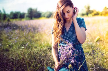 Bir sonbahar tarlasında elinde çiçeklerle bir kadının portresi