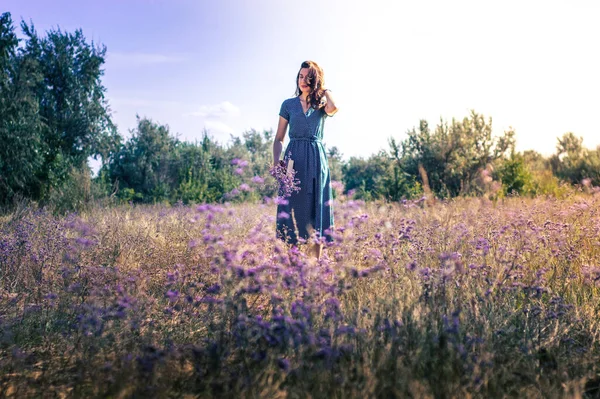 Bir sonbahar tarlasında elinde çiçeklerle bir kadının portresi