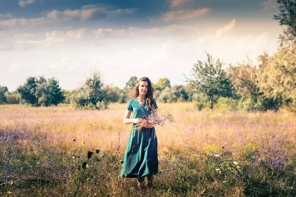 Bir sonbahar tarlasında elinde çiçeklerle bir kadının portresi