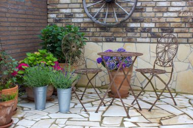 Akdeniz tarzında bahçede güzel bir yer. Izgaralı tuğla duvar ve çiçekli tencereler.