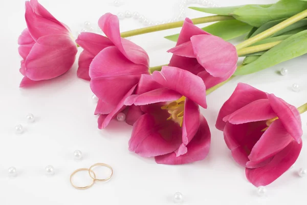 Красные тюльпаны, обручальные кольца, духи и бусы — стоковое фото