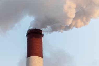 Buhar bulutlarında endüstriyel bir baca. Güneşli kış günü.