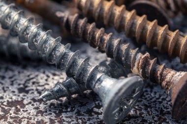 Çamur ve pasla kaplı bir avuç eski vida. Makro fotoğrafı vidalıyor. Yapı soyutlaması. Sanayi geçmişi.