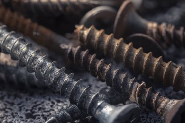 Çamur ve pasla kaplı bir avuç eski vida. Makro fotoğrafı vidalıyor. Yapı soyutlaması. Sanayi geçmişi.