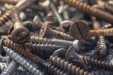 Çamur ve pasla kaplı bir avuç eski vida. Makro fotoğrafı vidalıyor. Yapı soyutlaması. Sanayi geçmişi.