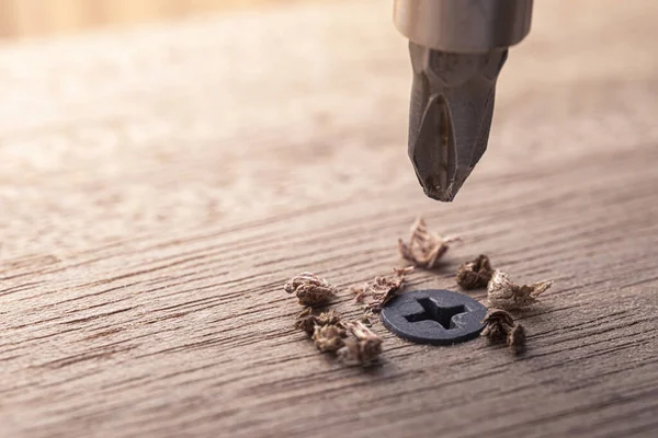 Screwdriver screw in a wood oaks plank. Self-tapping screw for PH2 bit. Screws macro photo. Construction abstraction. Industrial background.