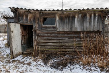 Çürük kalasları olan eski bir ahşap malzeme deposu. Baharın başlarında, yerde kar kalıntıları vardı..