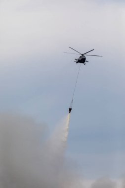 Yangın yüzünden dumanlı bir su tankı olan itfaiye helikopteri. Büyük bir yangından çıkan dumanlar..