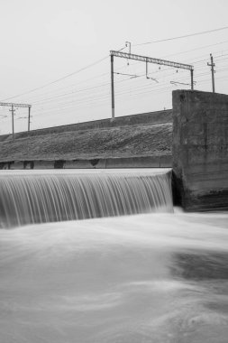 Demiryolunun yakınındaki beton bir kanalda boy farkı. Uzun pozlu siyah beyaz fotoğraf.