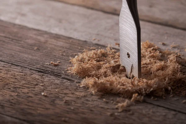 Feather wood drill bit on wooden background. Drill bit for wood on natural wood background. Woodworking background.