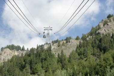 çam ağaçları ile çevrili bir dağ yükseklikleri için teleferik yükselir