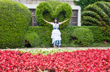 Kalp ve labirent masal çizimi çiçekli ağaç şeklinde. Bir kalp, Bahçe, çiçek yatağı ile kırmızı çiçek Begonya şeklinde bir çalı yakın bahçesinde kız