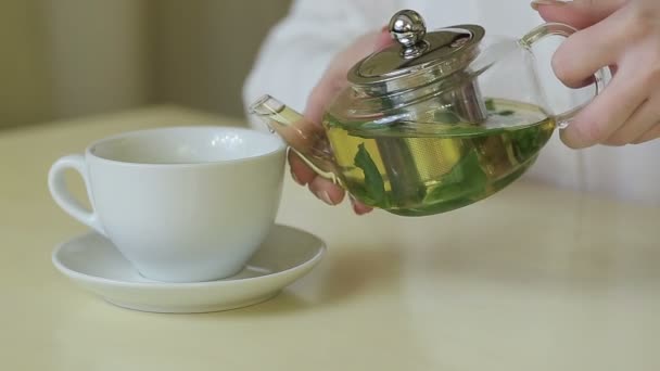 Kvinnan häller grönt te från tekanna — Stockvideo