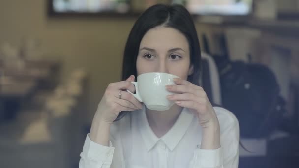 Junge Frau trinkt Tee in einem Café — Stockvideo