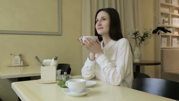 Mujer joven bebiendo té en un café — Vídeo de stock