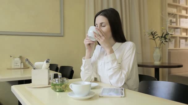 Mujer joven bebiendo té en un café — Vídeo de stock