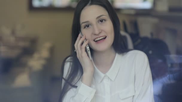 Ung kvinna talar i mobiltelefon i café — Stockvideo