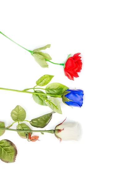 Rosas de plástico vermelho azul e branco sobre fundo branco . — Fotografia de Stock