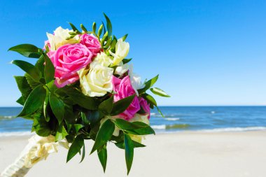 Düğün buketi bir arka planda gökyüzü ve deniz.