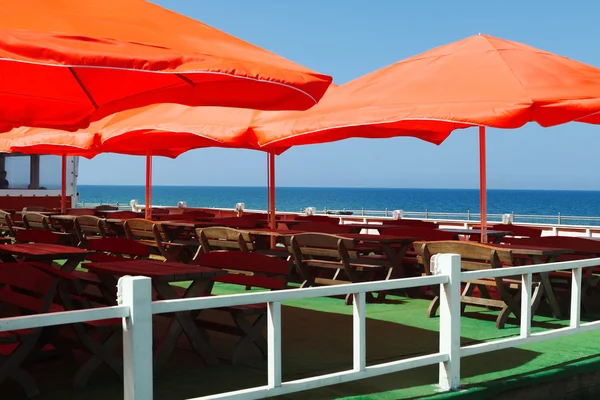 Das Café mit den orangefarbenen Sonnenschirmen am Meer. — Stockfoto