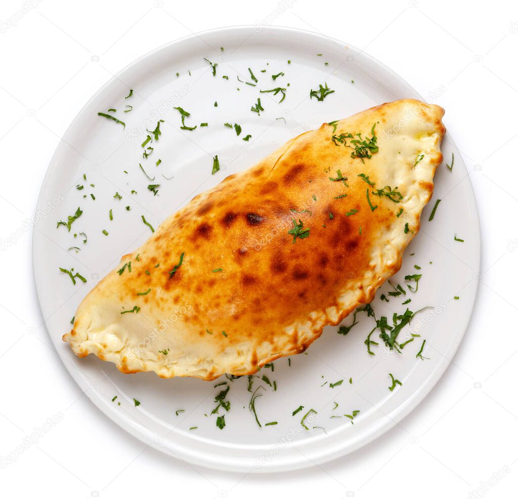 Italian closed pizza Calzone on a large white plate, isolated on white background. Top view